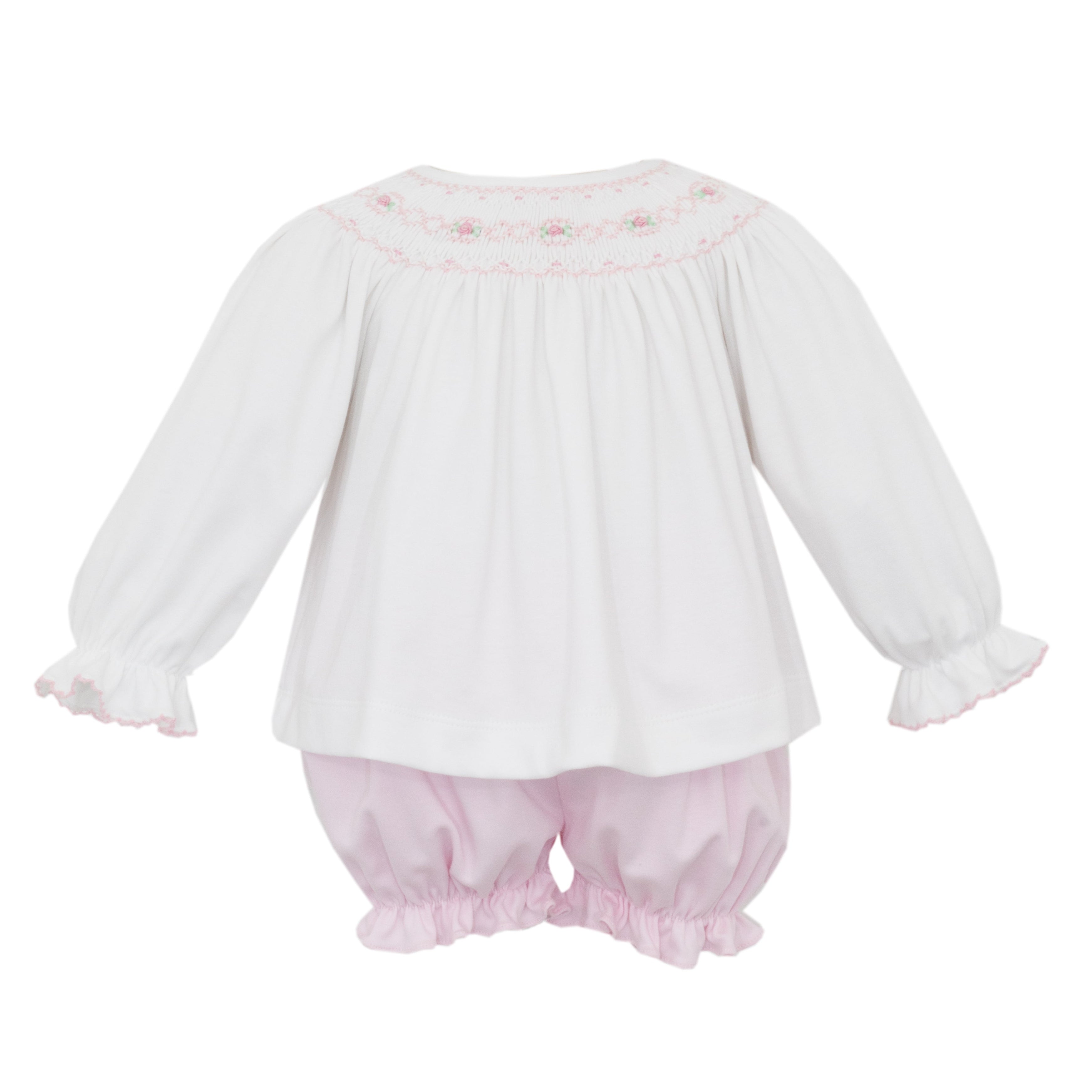 White baby blouse with pink floral smocking and pink bloomers on a white background